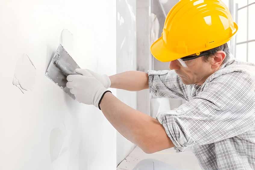 Worker applying stucco to an interior wall